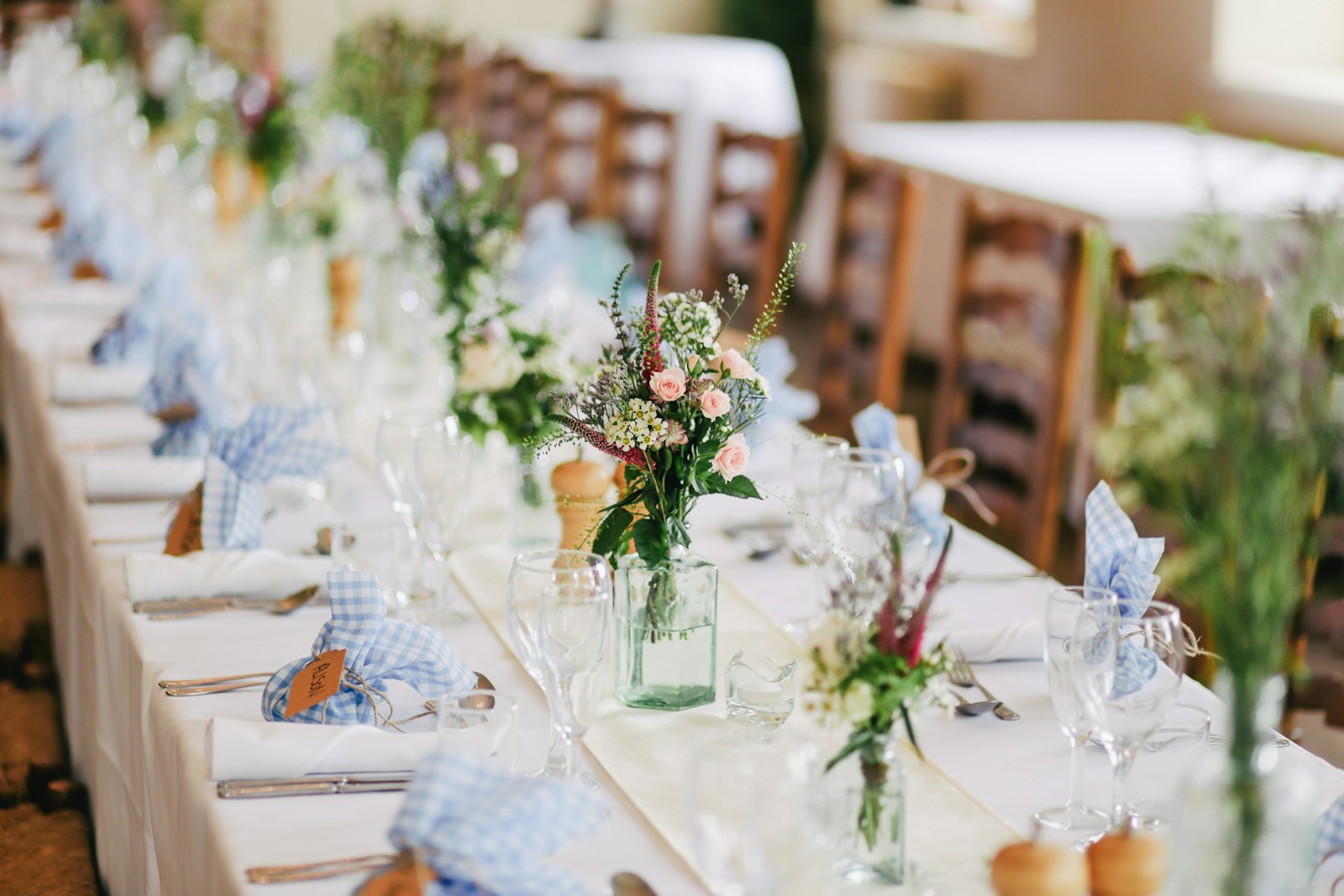Long tablescape with centerpieces under bistro lights at golden hour.